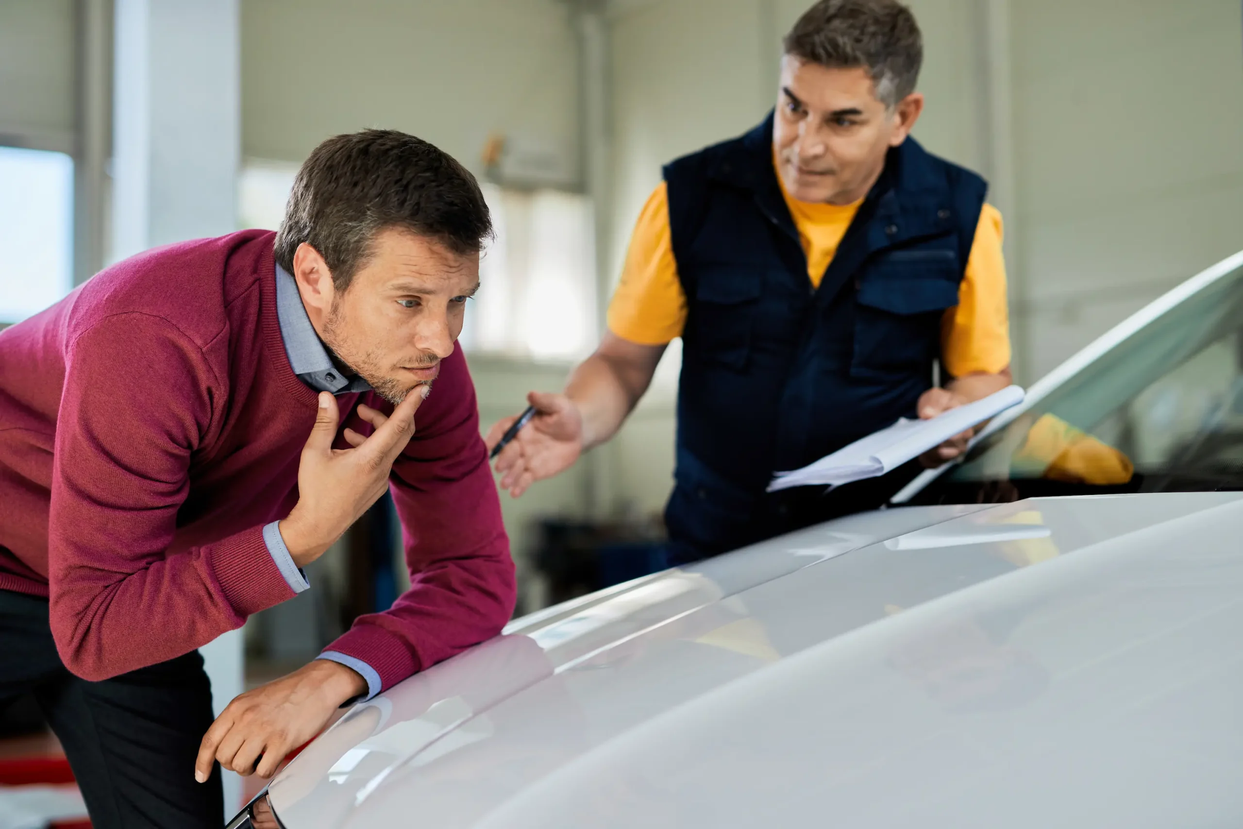 uncertain-man-examining-his-car-hood-while-mechanic-is-talking-his-auto-repair-shop - Estes Pro Paint auto body repair near me